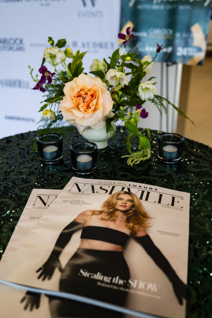 Modern Luxury Nashville magazine displayed on a green table with floral arrangement during the one-year anniversary event at Carlock Motors.