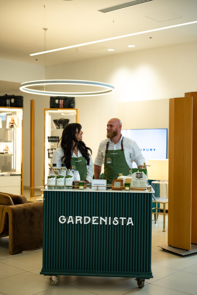 Gardenista cocktail bar with branded green bar cart and staff serving drinks at the Modern Luxury Nashville one-year anniversary event inside Carlock Motors.