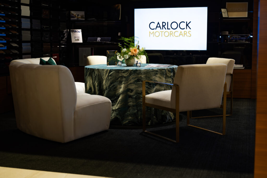 Conversation seating area with cream chairs and green marbled table inside Carlock Motors during the Modern Luxury Nashville one-year anniversary event.