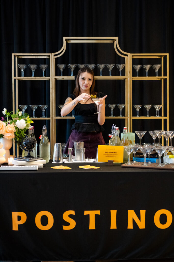 Bartender serving martinis at the Postino bar during the Modern Luxury Nashville one-year anniversary event at Carlock Motors.