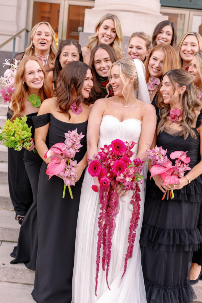 Bride with bridesmaids in black dresses holding pink and fuchsia bouquets at Nashville wedding