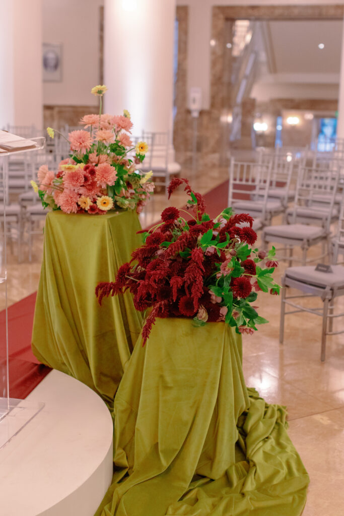 Ceremony floral arrangements with burgundy and blush flowers on chartreuse linens at Nashville Symphony wedding