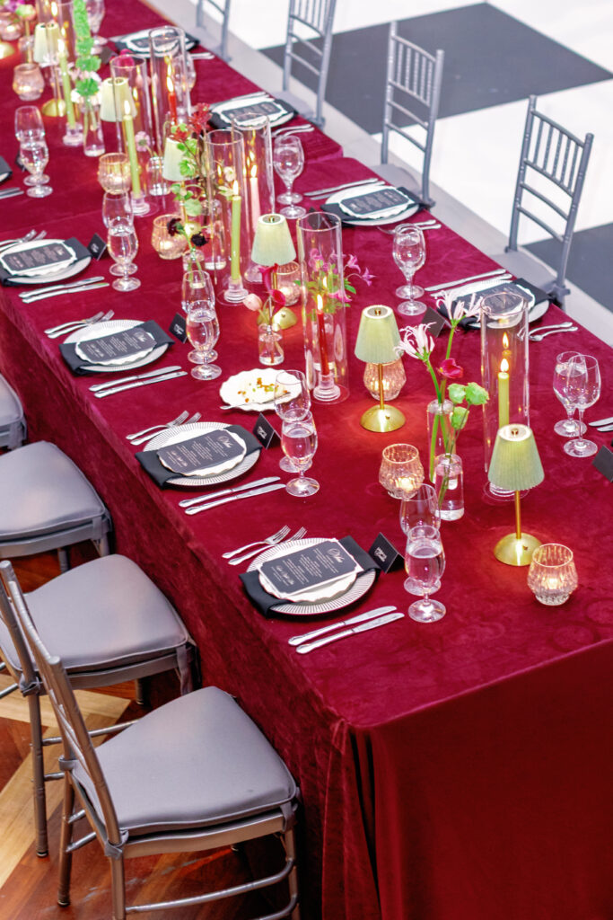 Burgundy velvet wedding table with candles, glassware, and black place settings at Nashville Symphony reception