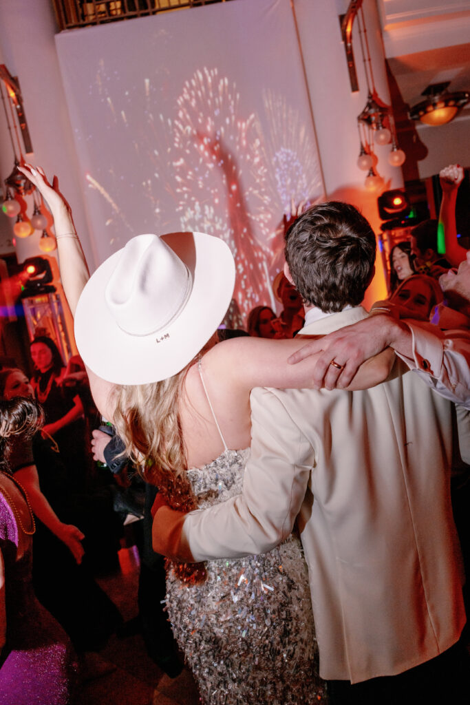 Bride and groom celebrating on dance floor during New Year’s Eve wedding with projected fireworks countdown in Nashville